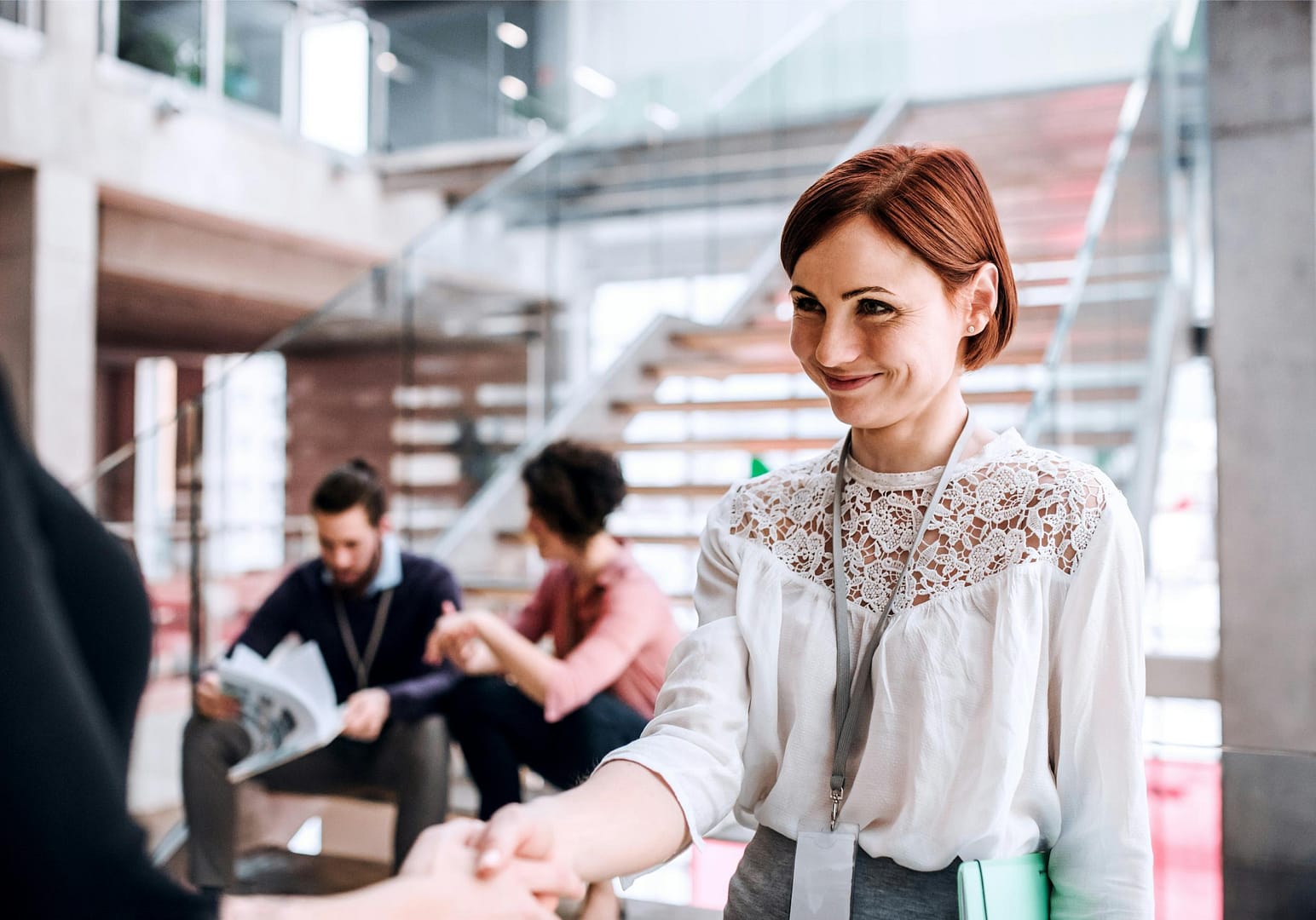 Professional woman smiling and shaking colleagues hand