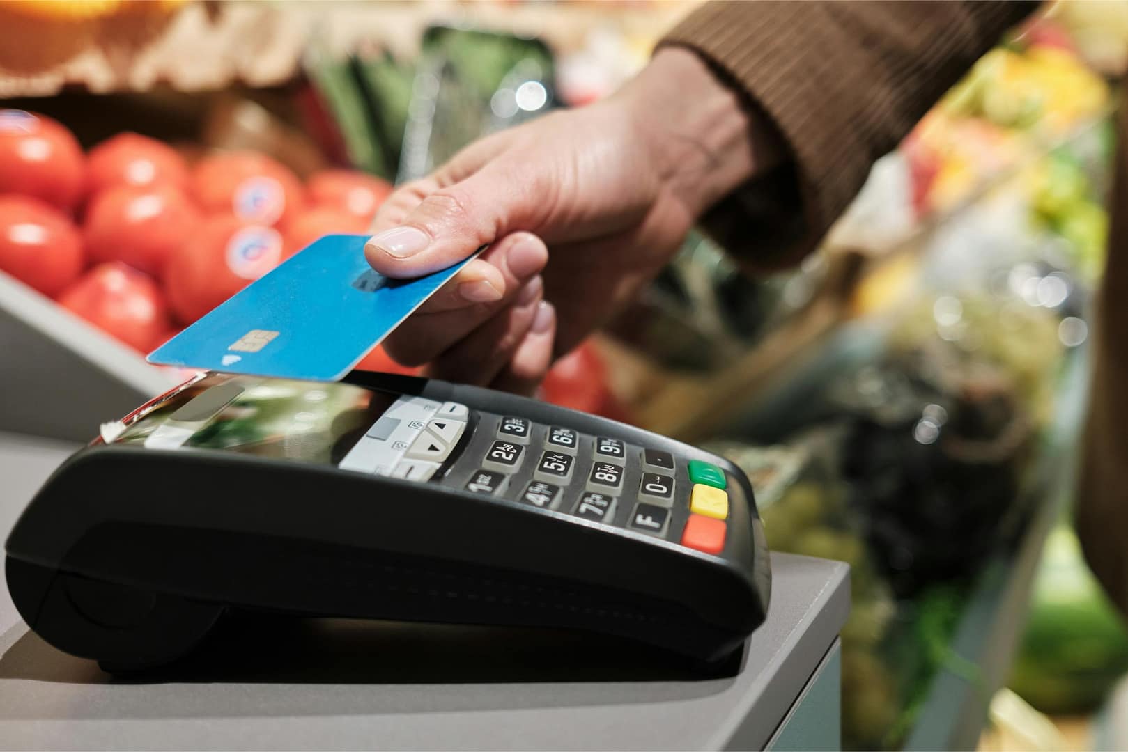 Person using credit card to pay at grocery store payment terminal
