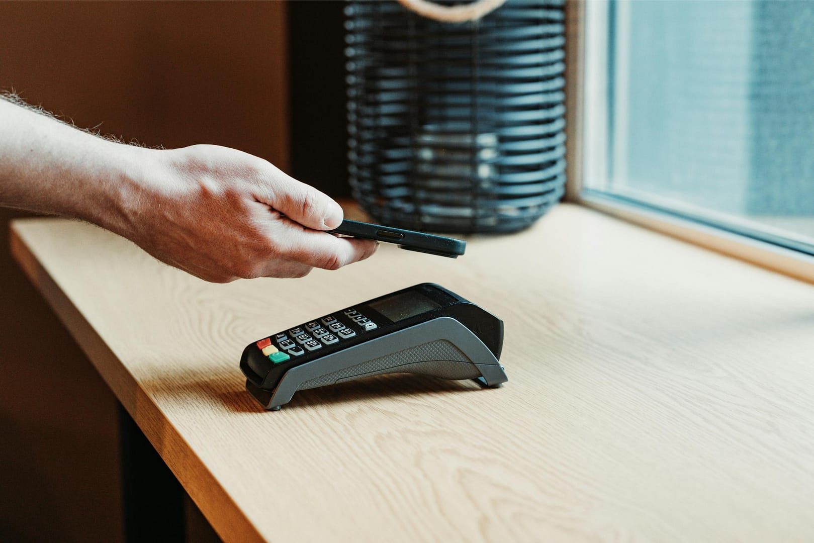 Man using smartphone to pay at payment terminal