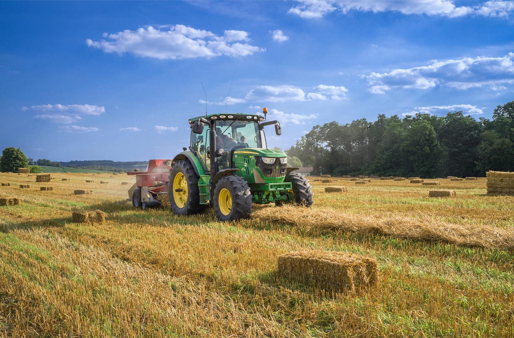 Farmer driving tractor in field baling hay