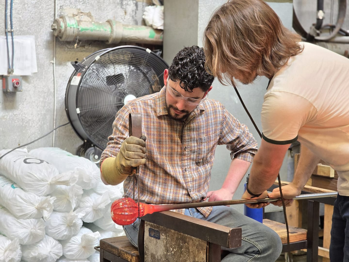 two men working on glassblowing piece