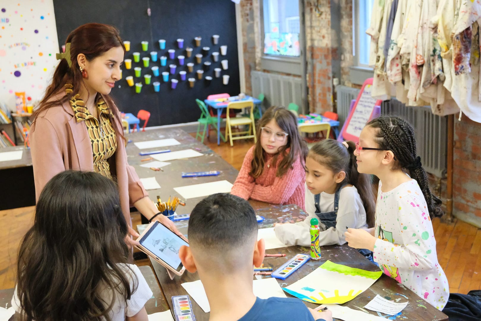 children look at teacher's ipad during art class
