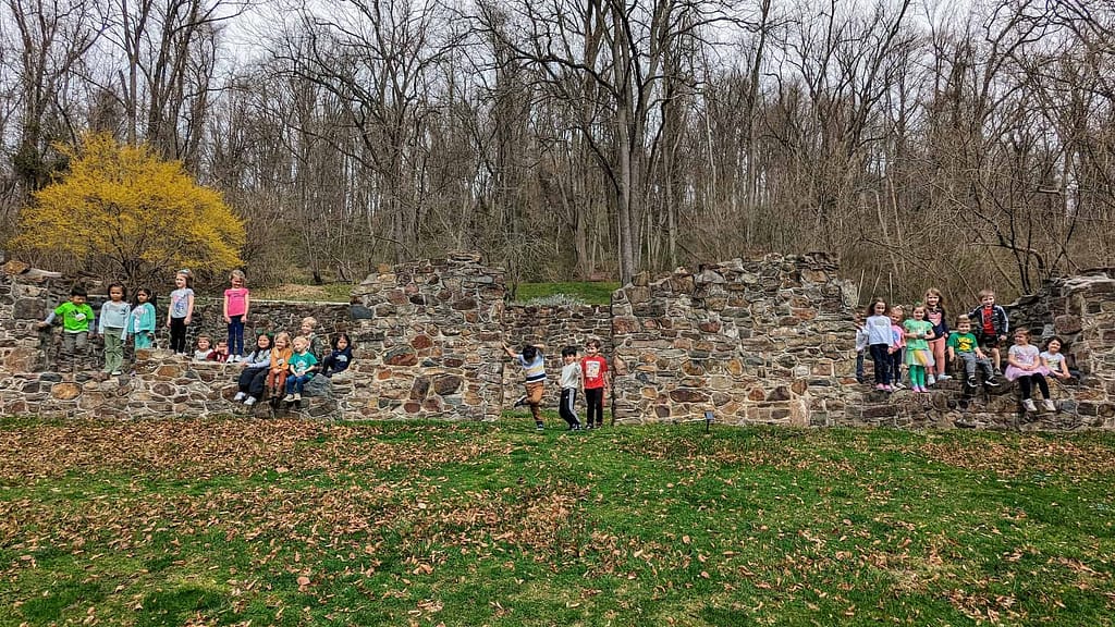 A group of youth programs participants pose while on a guided history tour in front of the preserved structure while touring the grounds of historic yellow springs