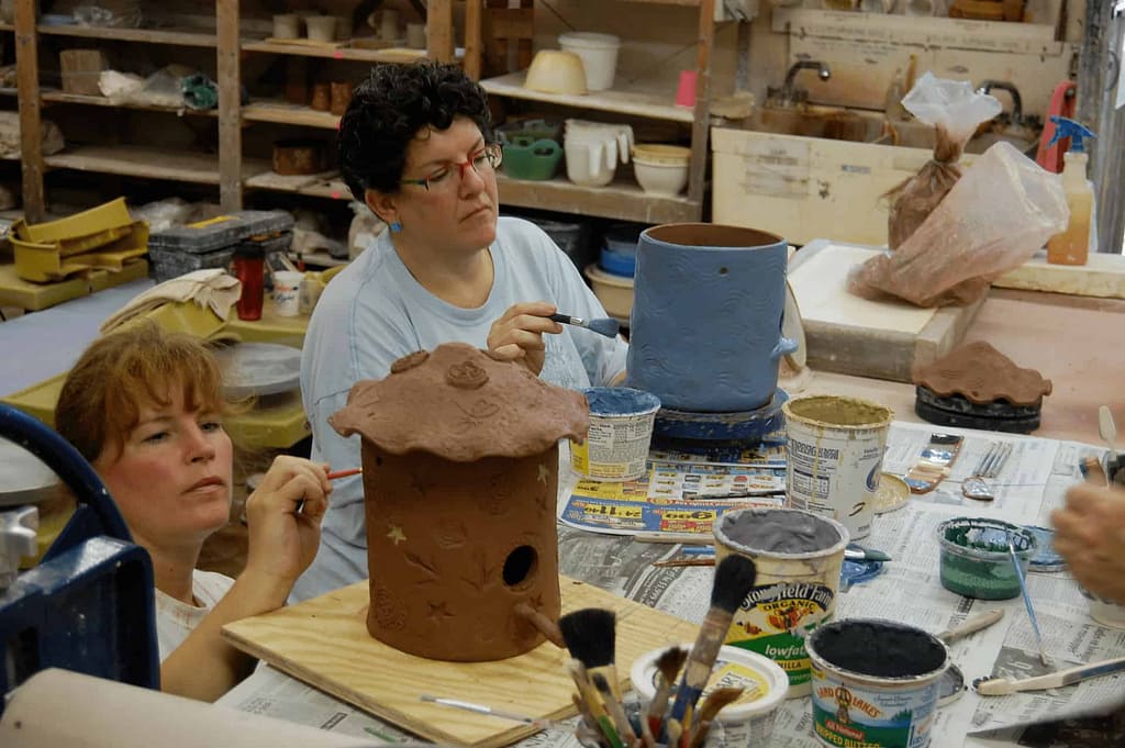 Students in a private group activity add color to a pottery piece made from ceramic clay in an adult community class.