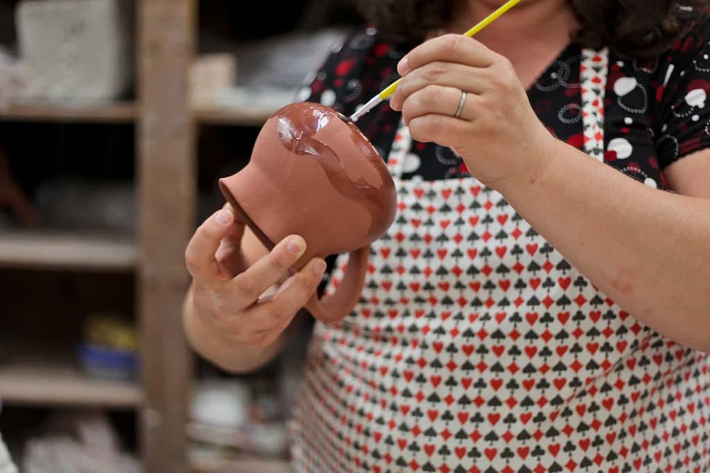 Students add color to a pottery piece made from ceramic clay in an adult community class.