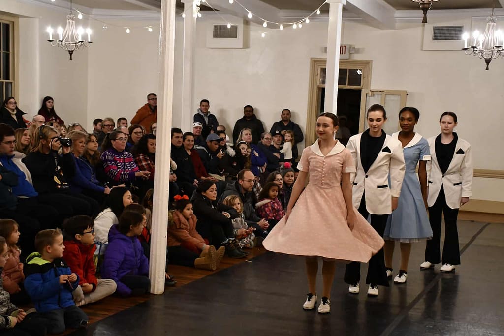 Dancers prepare for a performance for a holiday venue in the event space for the village on the national register of historic Places