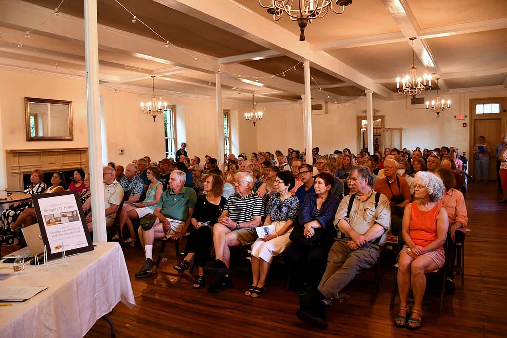 A crowded room of visitors listen to a presentation about historic preservation in the event space and venue