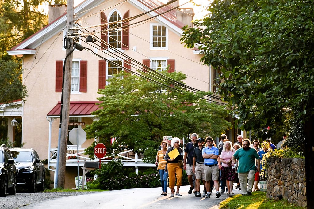 Tour group walks through the preserved village as part of a community experience in the village on the national register of historic places