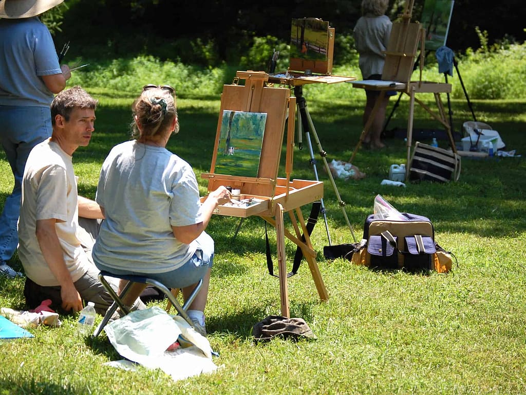 A teacher shares information with a student in a community arts class focused on painting en plein air.