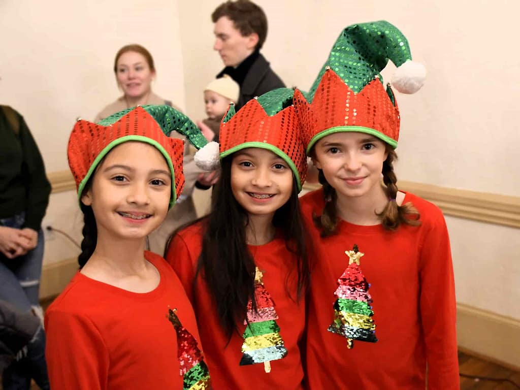 Three young visitors are dressed as elves while celebrating the holidays at the National Register of Historic Places holiday event.