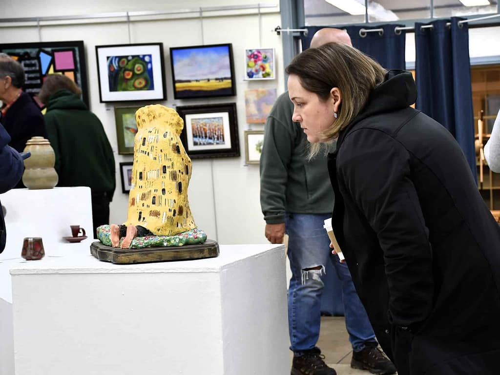 A woman looks at a ceramics sculpture in a gallery at the member artists' show submitted through an artist call and sale.