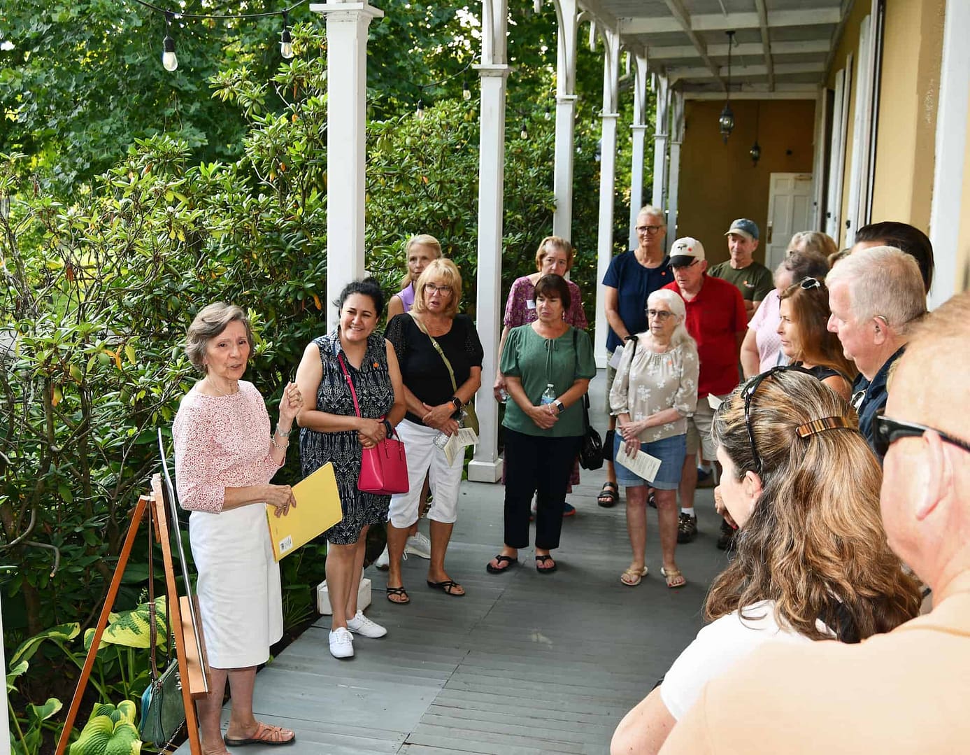 A volunteer presents information for a group of community members in front of the preserved building in the village on the national register of historic places