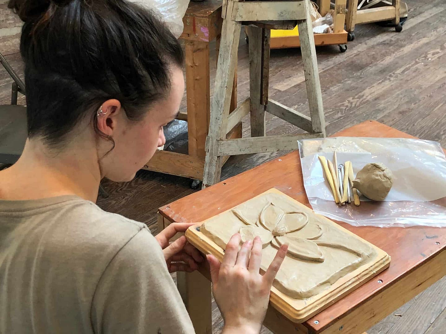 Youth and Teen student works on a ceramic sculpture while participating in a camp program and class