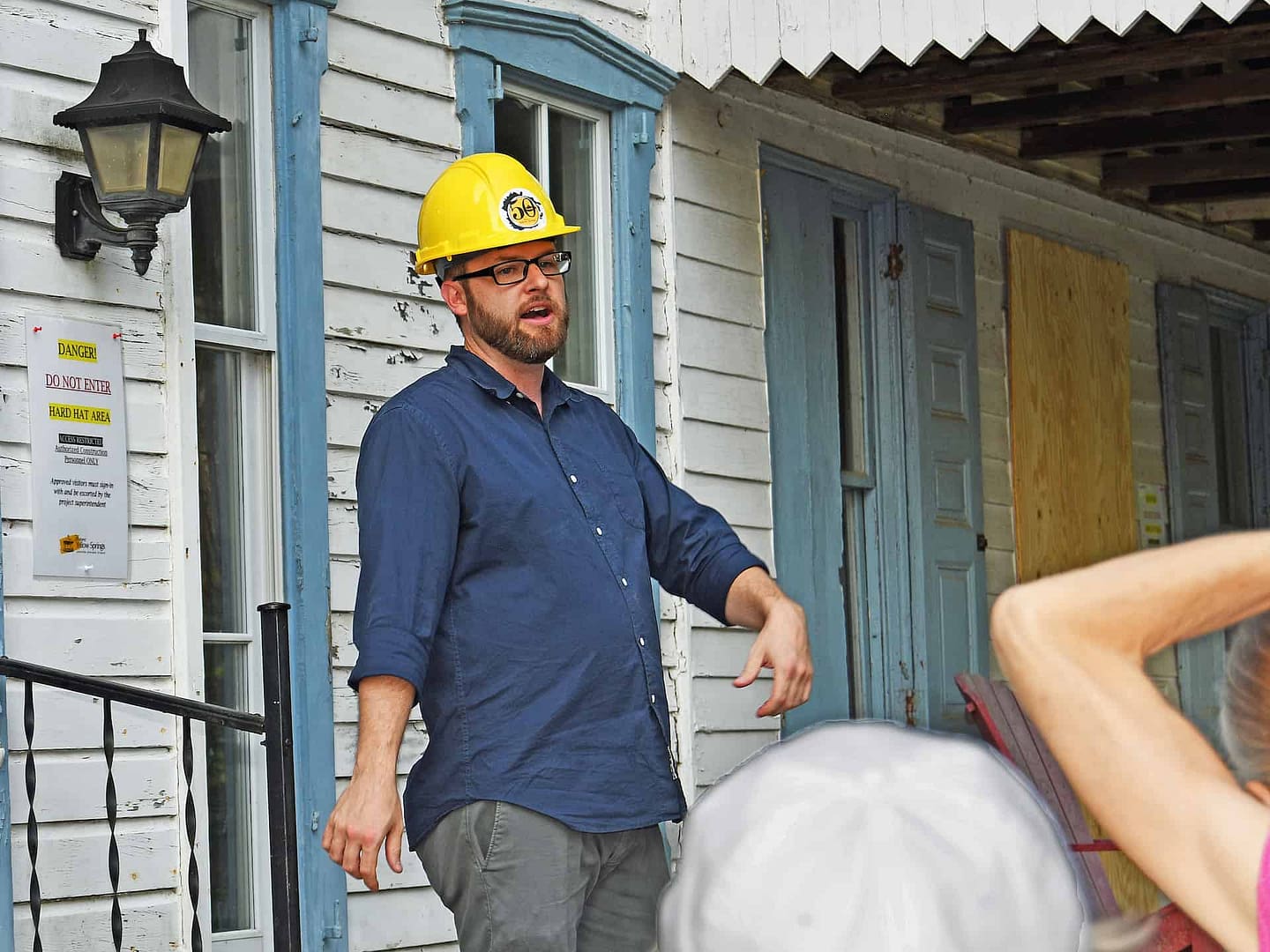 A volunteer presents information for a group of community members in front of the preserved building in the village on the national register of historic places