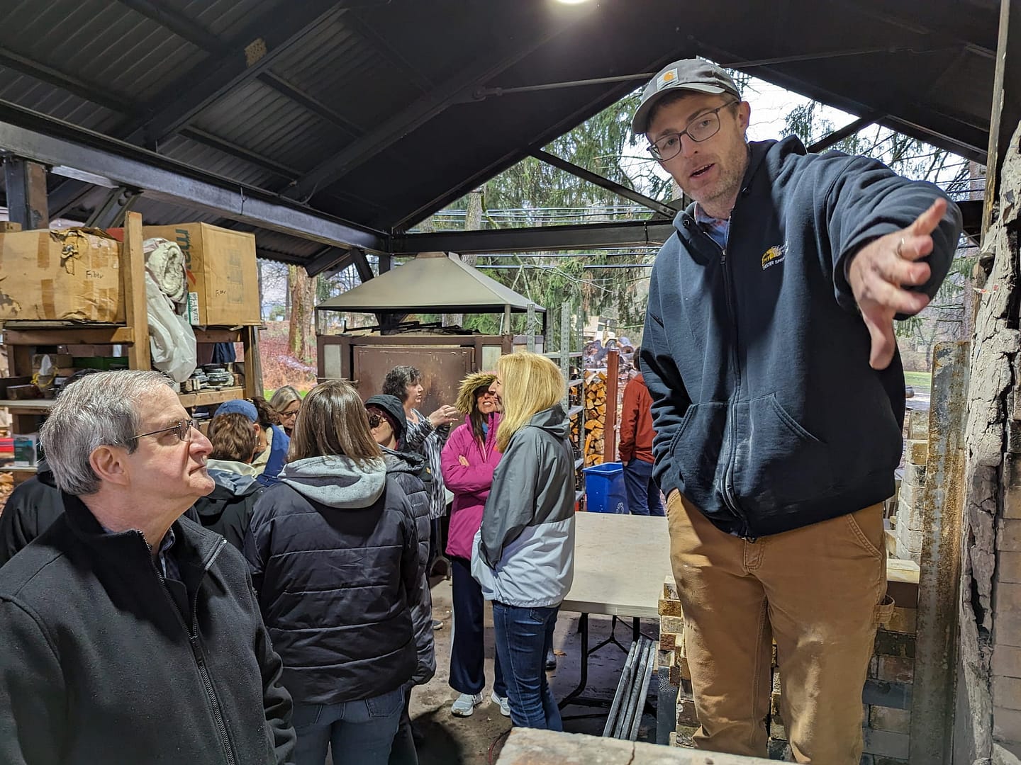 Ceramics teachers share their knowledge with community visitors by explaining the pottery process at the woodfire kiln.