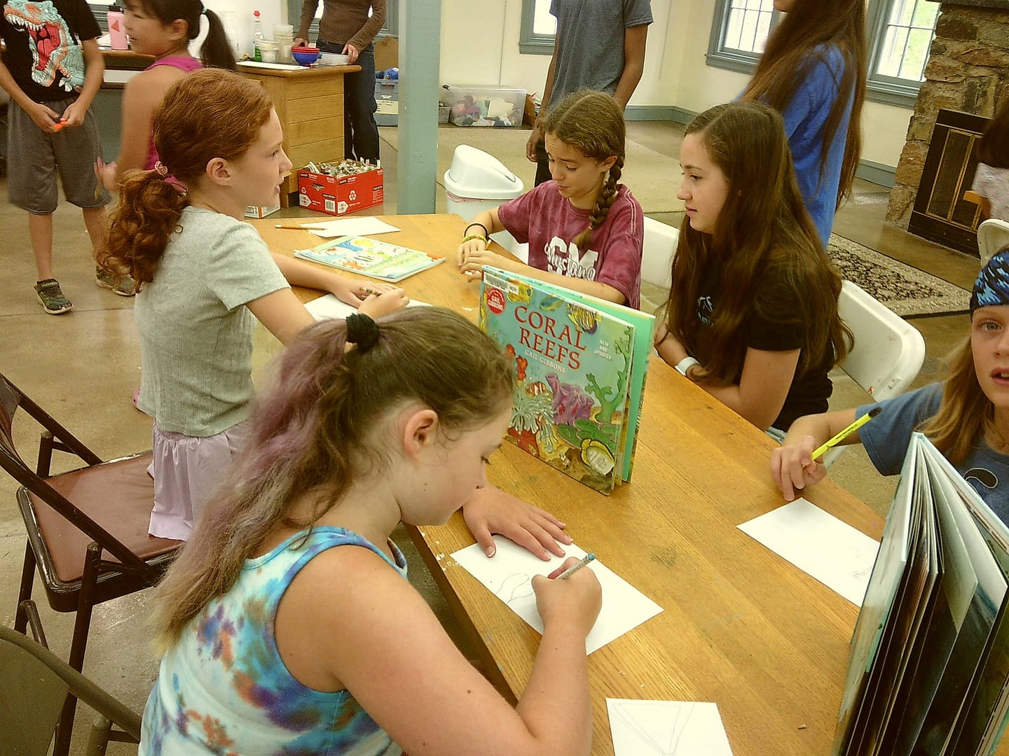 Youth students use books to inspire drawings at summer camp.