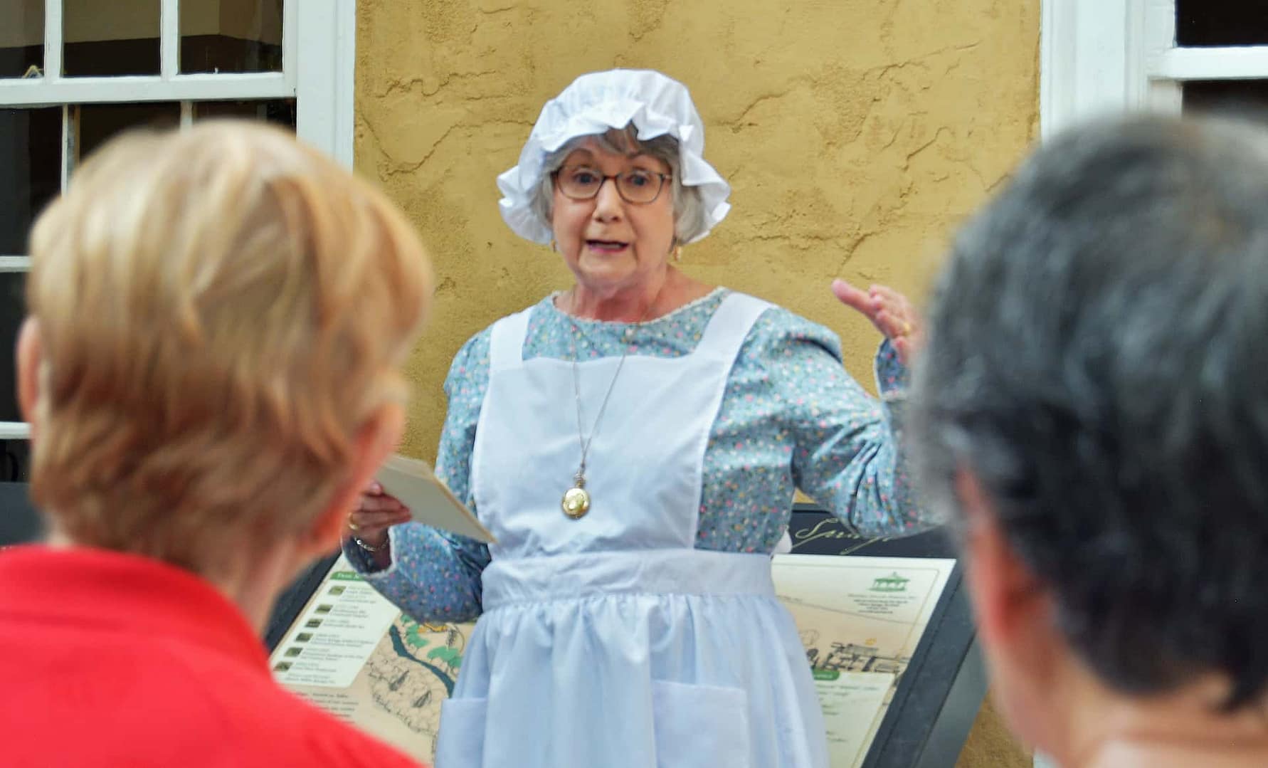 A volunteer presents information for a group of community members in front of the preserved building in the village on the national register of historic places