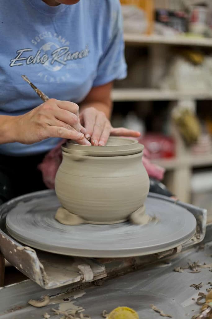 Students practice making pottery on the potter's wheel as part of a community class with ceramic clay