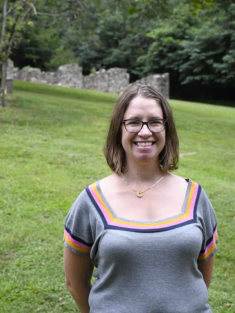 A staff member posing in front of the preserved historic ruins at historic yellow springs