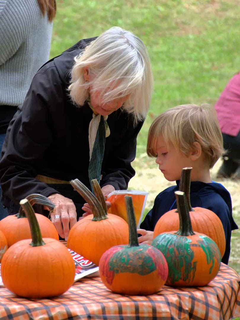 A youth participant and elderly participant select pumpkins at an art making activity in the village on the national register of historic places